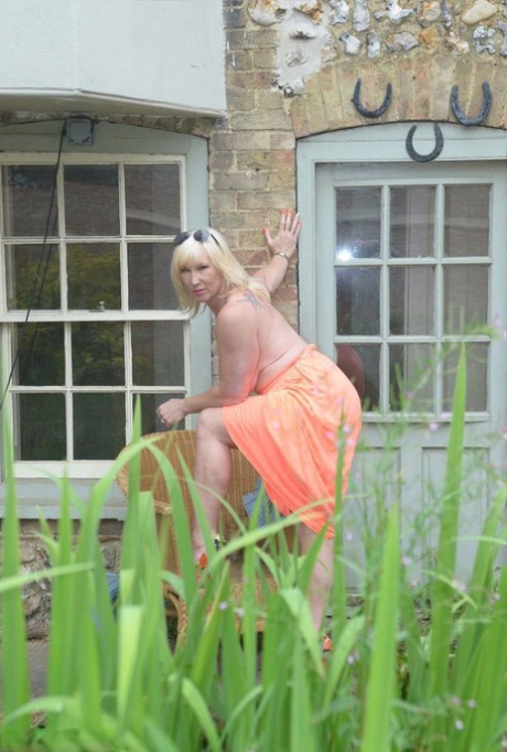 Big titted blonde Melody drops her dress outside to air her naked mature tits