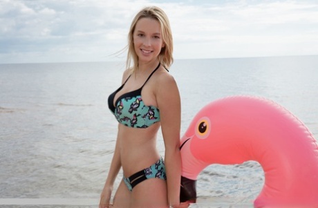 Young blonde with great legs takes off bikini for nude poses on inflatable