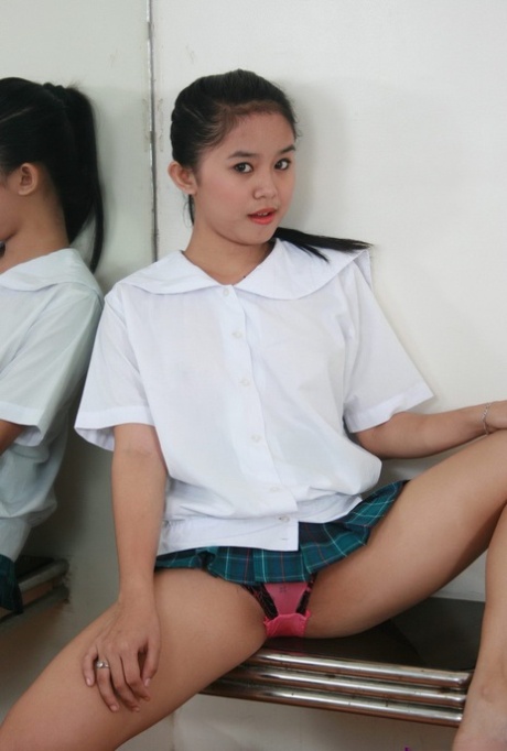 Barely legal Asian schoolgirl with full breasts showcases her pussy on bed