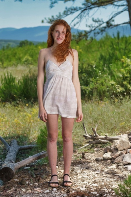 Natural redhead Foxy Lee plays with her naked pussy by a fire pit