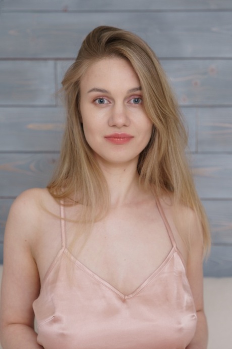 Young looking blonde Valerie unveils her full breasts on top of her bed