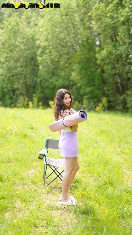 Brunette teen Lola Bredly unveils her full breasts while going nude in a field