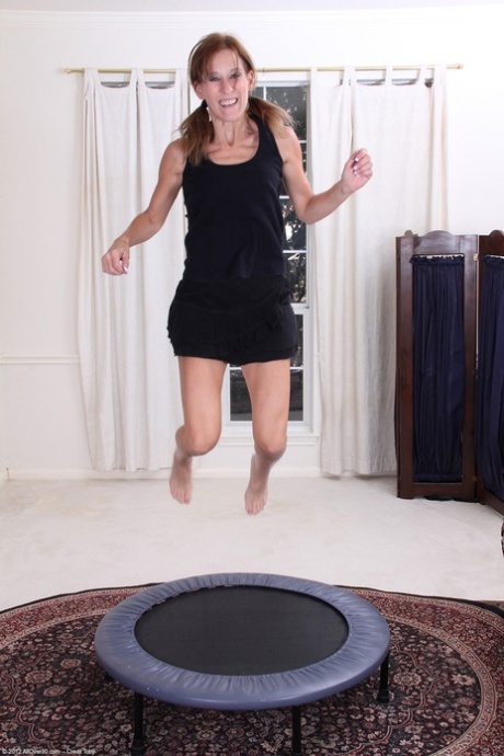 Mature Jay Dee removes her clothes on an indoor trampoline and rubs her cunt