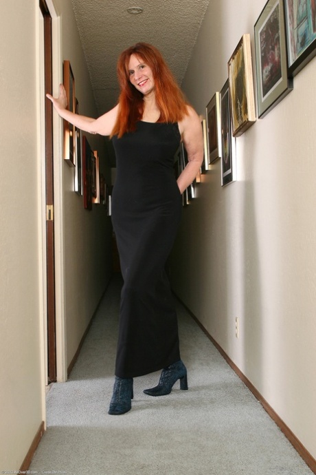 Redheaded mature Breeze lets out her massive juggs and poses in fishnets