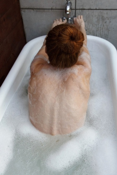 Petite redhead Wendy Patton strips fully naked and takes a bubble bath
